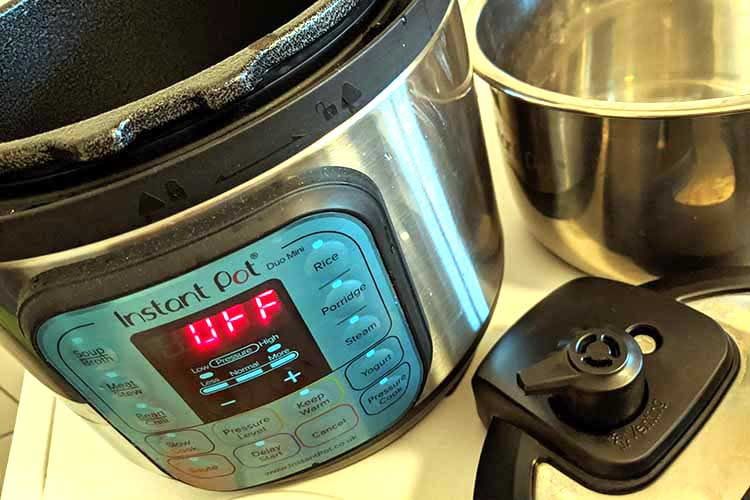 La pentola in acciaio inox viene inserita nella Instant Pot. Sulla destra del coperchio si possono vedere il rilascio del vapore e l'indicatore di pressione.