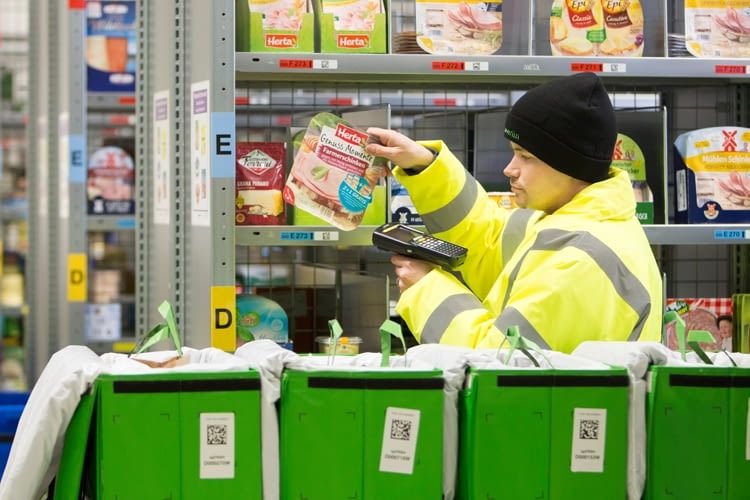 Mitarbeiter verpacken die Bestellungen manuell in Papiertüten