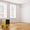 Gelb-schwarzer Bautrockner auf Holzboden in einem Raum mit zwei Fenstern und Wasserschaden an der Decke