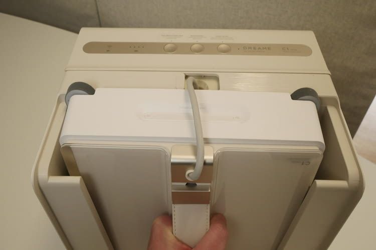 An dem ergonomischen Kunstledergriff wird der Dreame C1 Roboter aus der Station gehoben. An dem ergonomischen Kunstledergriff wird der Dreame C1 Roboter aus der Station gehoben.