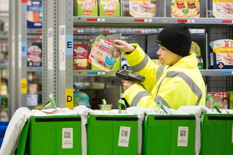 Mitarbeiter verpacken die Bestellungen manuell in Papiertüten Mitarbeiter verpacken die Bestellungen manuell in Papiertüten