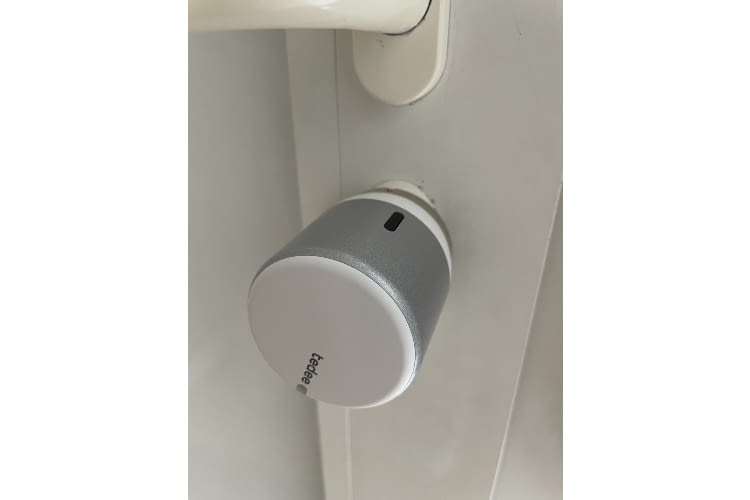 Über den schwarzen Knopf kann der silberne Rahmen entfernt werden. Über die weiße Vorderseite lässt sich auch per Hand auf- und abschließen Über den schwarzen Knopf kann der silberne Rahmen entfernt werden. Über die weiße Vorderseite lässt sich auch per Hand auf- und abschließen