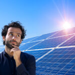 Nachdenklicher, junger Mann vor Solarmodulen