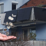 Münzen fallen von einem Balkonkraftwerk in eine offene Hand