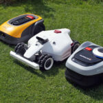 3 Mähroboter nebeneinander auf einer Rasenfläche