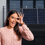 Junge Frau mit Sparschwein vor Solarmodul