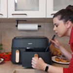 Tester blickt in offene Garschuble eines großen Airfryers