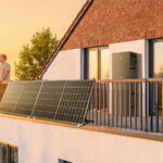Ein Mann steht auf einem Balkon, an dem Solarmodule hängen
