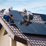 2 Männer montieren Solarmodule auf einem Hausdach