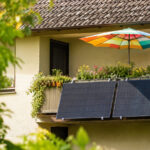 Sonniger Balkonk mit vielen Pflanzen, Solarmodulen und Sonnenschirm