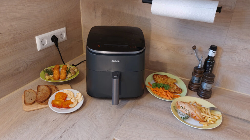 cosori-turboblaze-einzeltest-erfahrungen COSORI TurboBlaze umgeben von Pommes, Putenfilet, Kartoffelecken, Karotten und weiteren Speisen