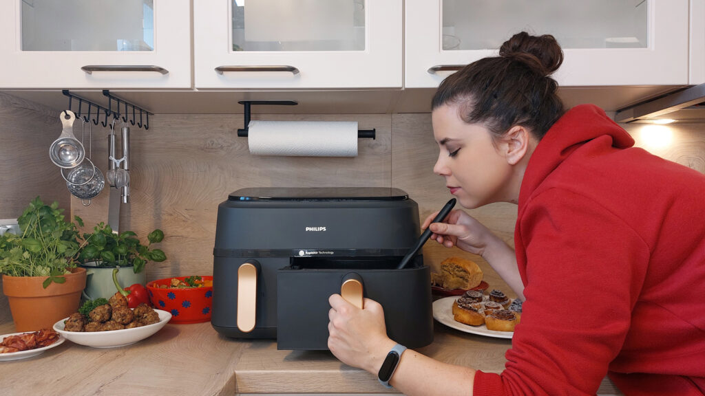 philips-series-3000-praxistest-von-mariella Frau blickt in einen halb geöffneten Airfryer und rührt darin herum