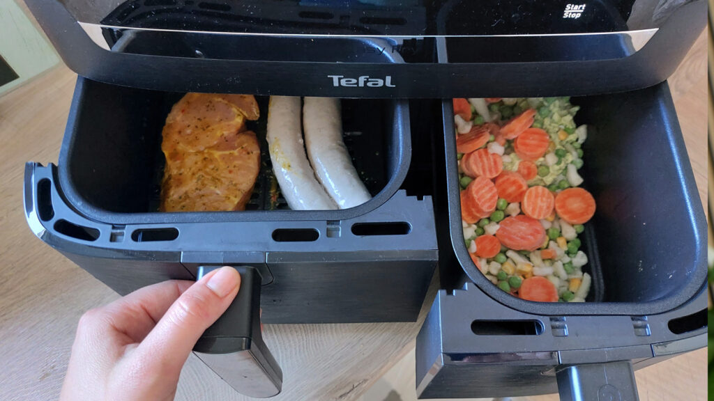 wie-viel-essen-passt-in-eine-heissluftfritteuse Zwei Garkörbe mit Fleisch, Wurst und Tiefkühlgemüse