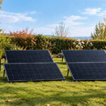 Vier Solarmodule auf einer Rasenfläche, daneben ein Solakon Speicher