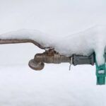 Verschneiter Außenwasserhahn: Leitungen im Garten sollten vor dem Winter abgesperrt und entleert werden.