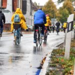 Radfahrer in Regenkleidung auf nasser Straße im Herbst