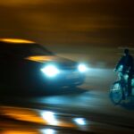 Radfahrer mit eingeschaltetem Frontlicht bei Nacht im Stadtverkehr