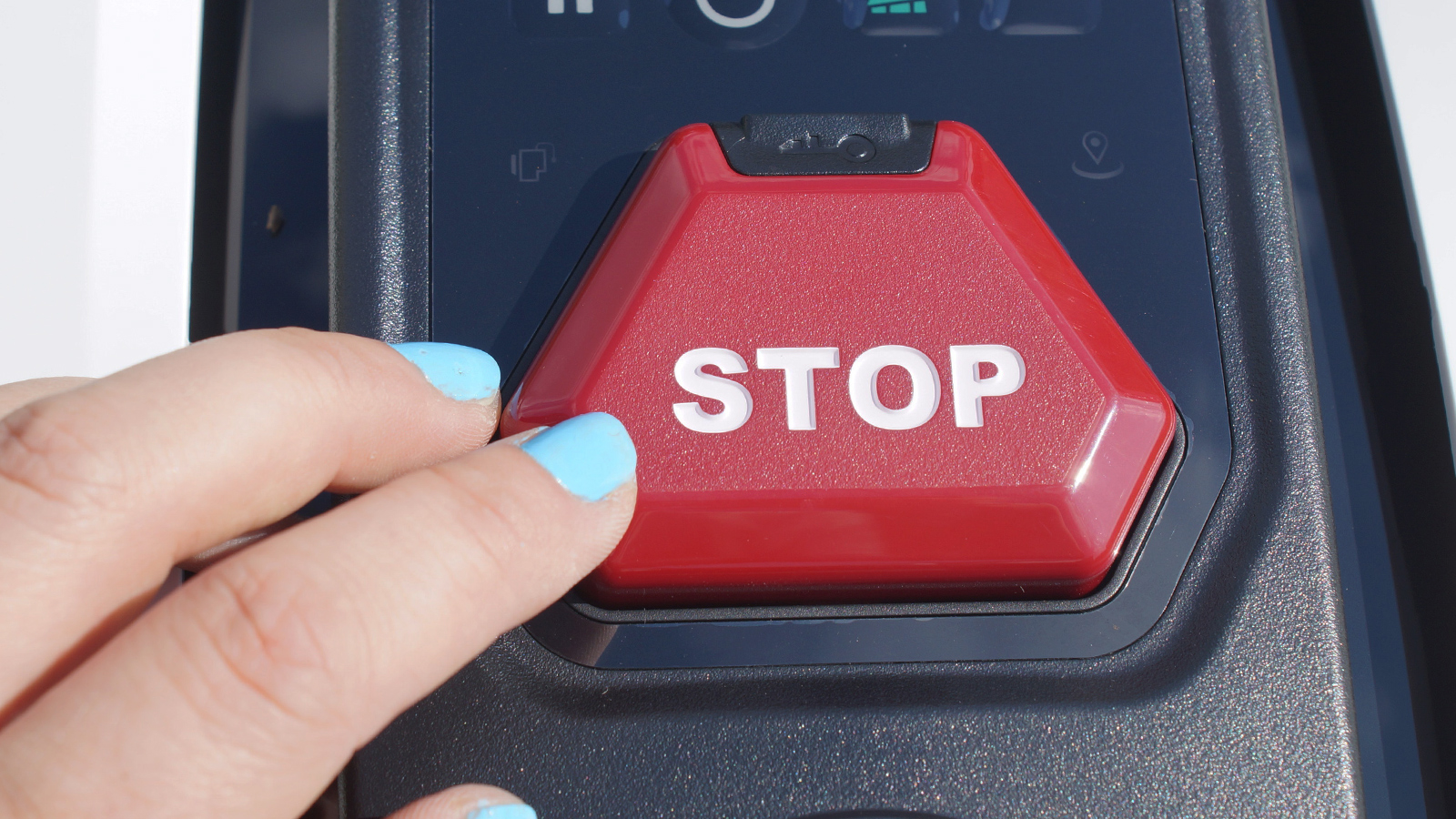 Finger drückt die rote Stopptaste auf dem Gehäuse eines Mähroboters